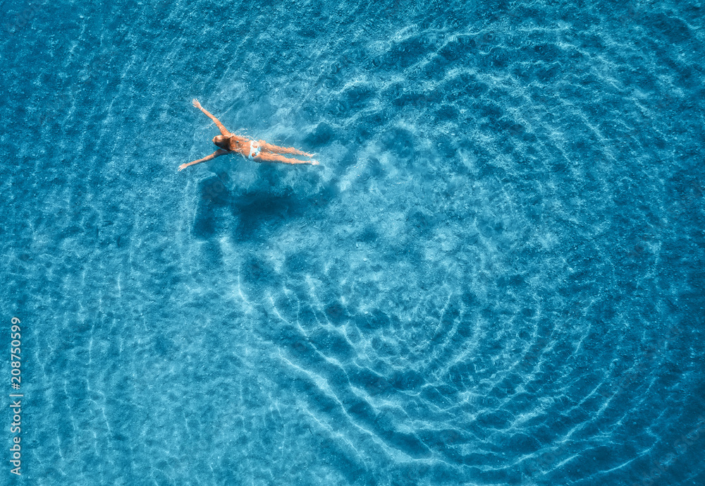 马尔代夫日落时游泳女子的鸟瞰图。地中海。年轻g的空中海景