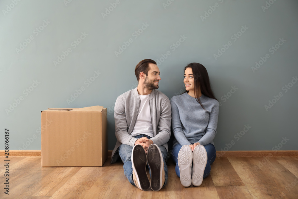 年轻夫妇坐在室内包厢附近的地板上。搬进新房子