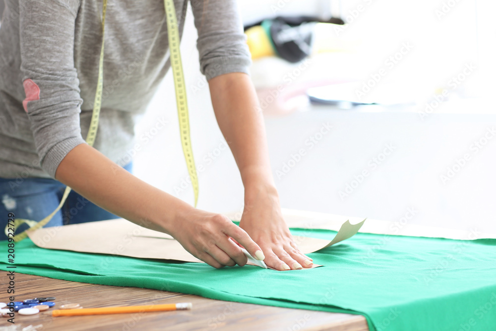 年轻的女裁缝在工作室里用缝纫图案工作