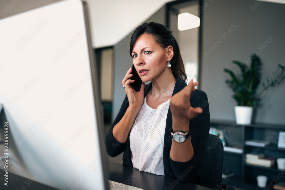 女高管看着电脑屏幕，在电话里认真交谈。