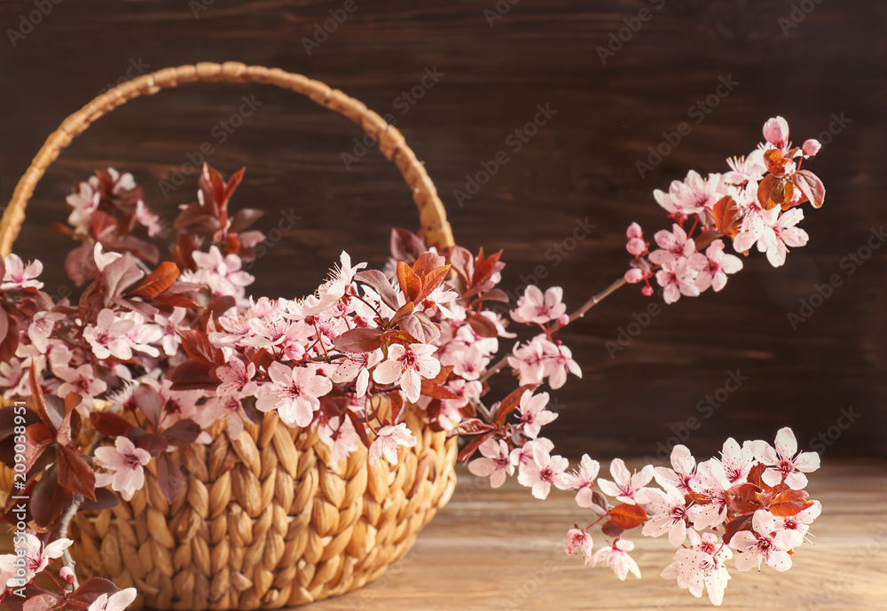 木桌上有美丽的开花树枝的柳条篮