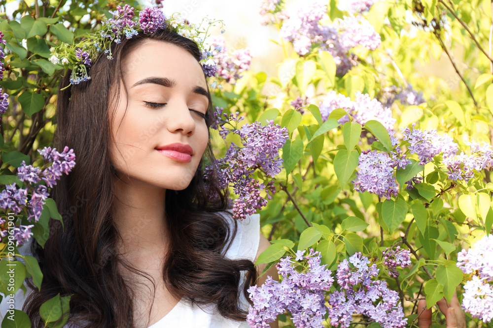 阳光明媚的春日，美丽的年轻女子在盛开的灌木旁戴着花环