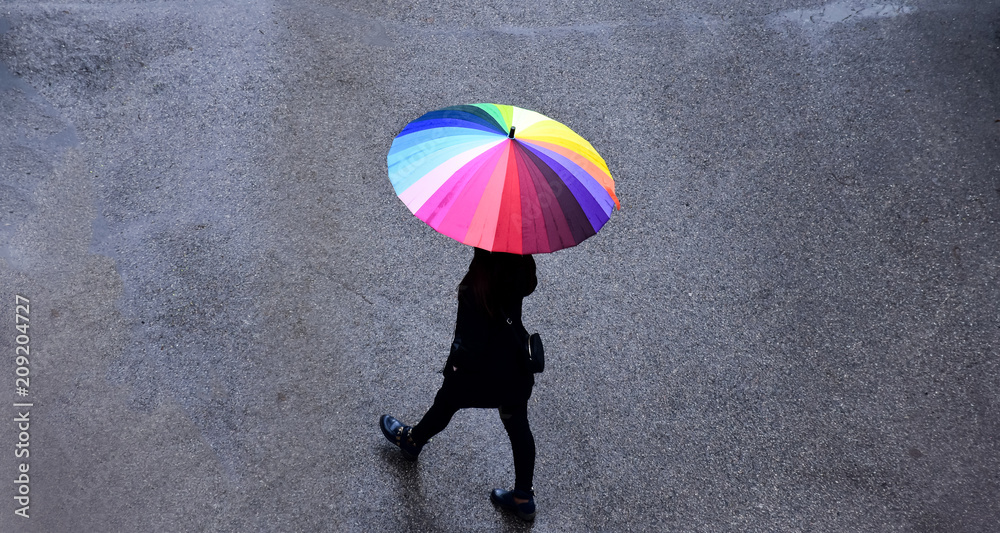 Rainy weather in Almaty, Kazakhstan. A beautiful girl with a cheerful umbrella is walking along the 