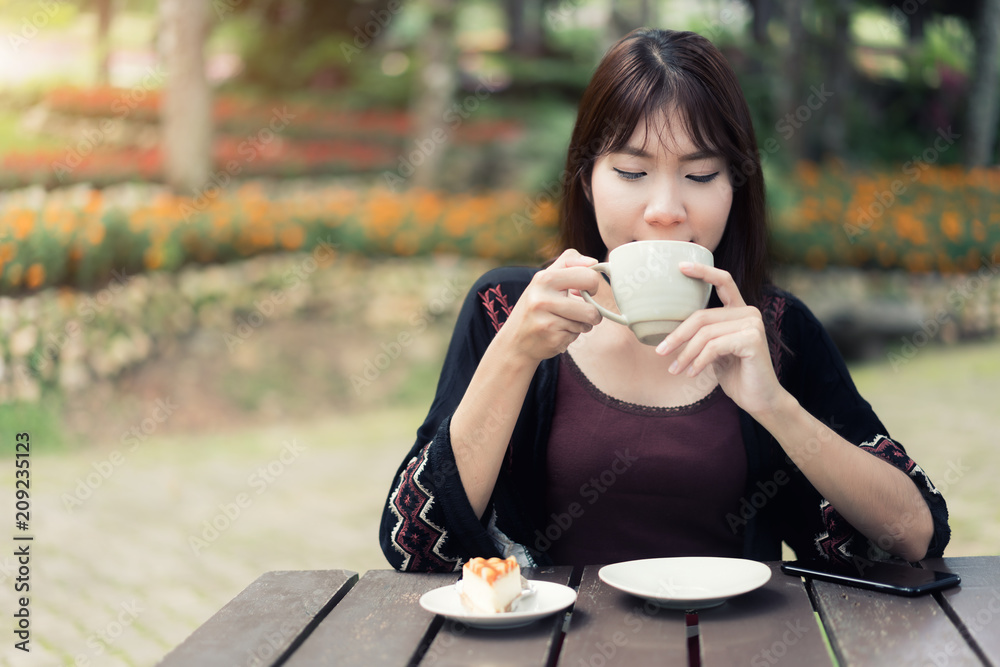 亚洲女性在家里的花园里喝杯咖啡放松身心，精神焕发。