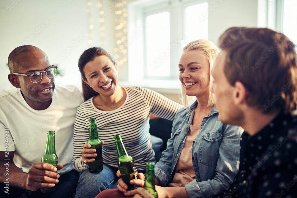 Laughing young businesspeople drinking beers after work in an of