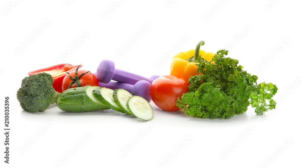 白色背景的新鲜蔬菜和哑铃。减肥食品