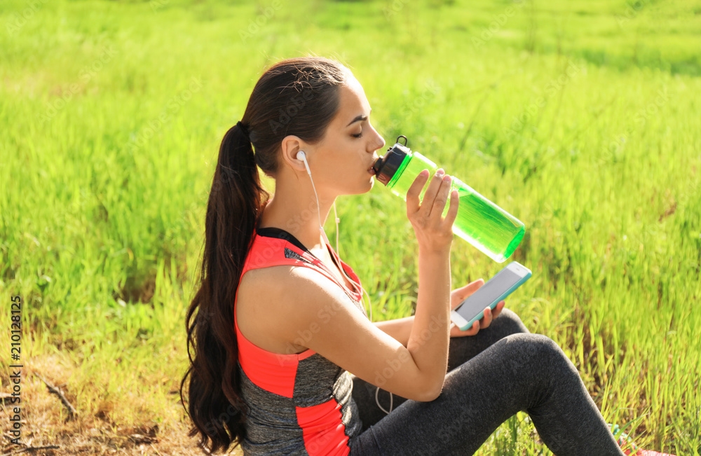 运动型年轻女子在公园跑步后喝水