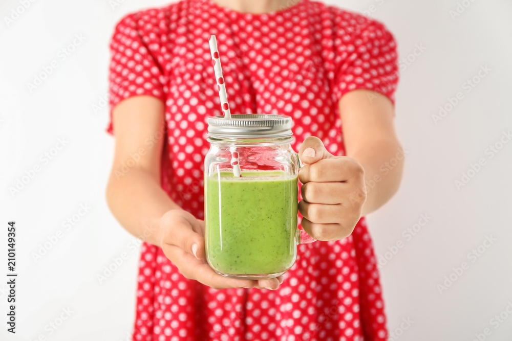 Woman holding mason jar with tasty smoothie on white background