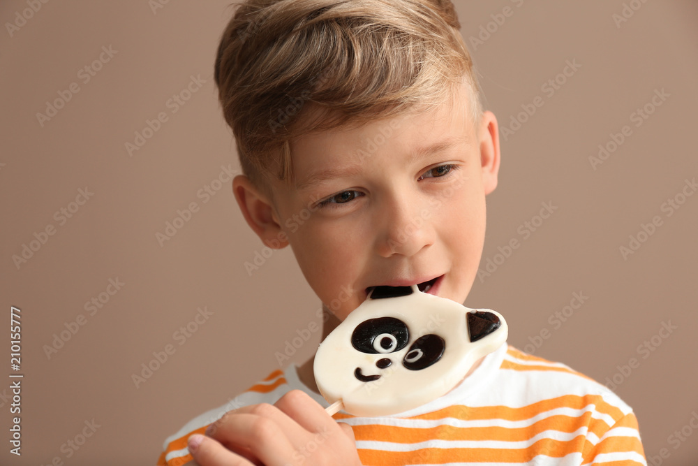 可爱的小男孩在彩色背景上吃棒棒糖