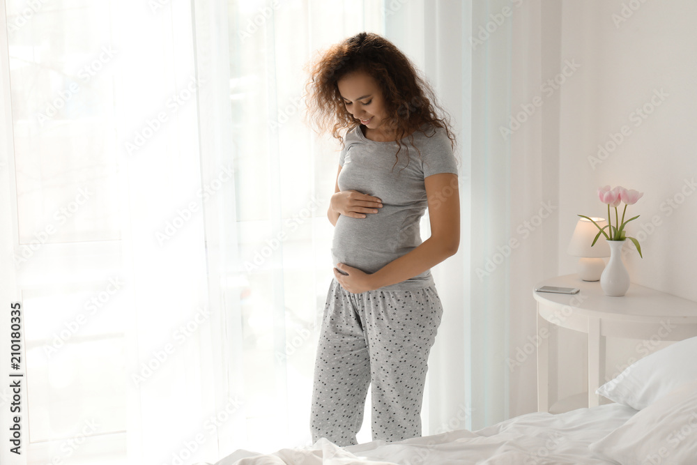 卧室里美丽的非洲裔孕妇的早晨
