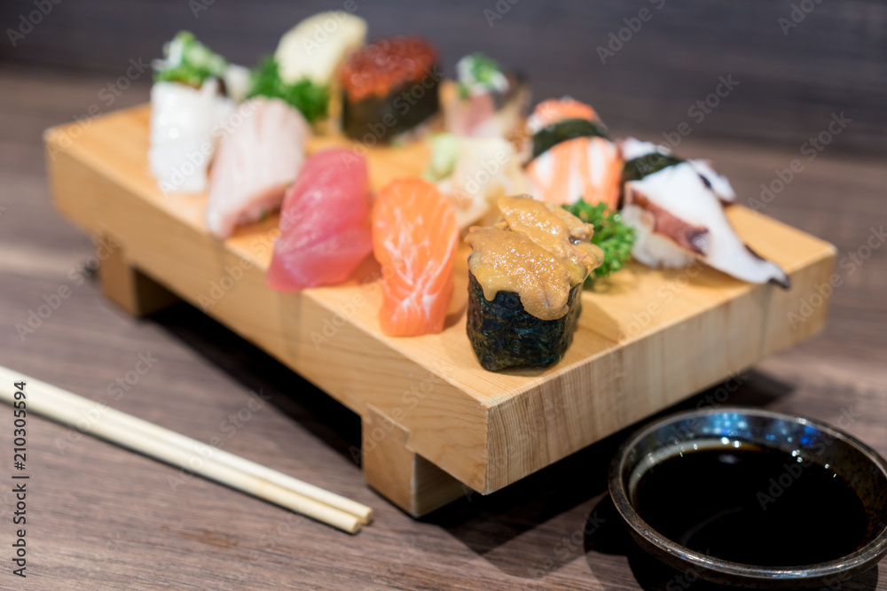 特写寿司和生鱼片混合在黑色木桌上的木盘上。日本食物。