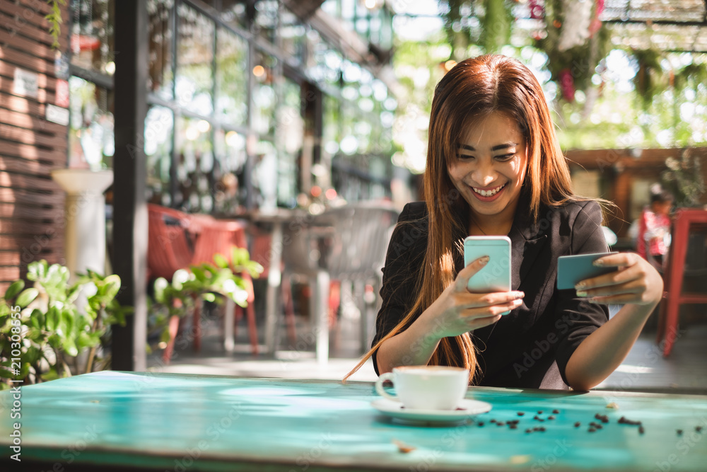 在咖啡店咖啡厅使用智能手机和信用卡在线购物的亚洲年轻美女
