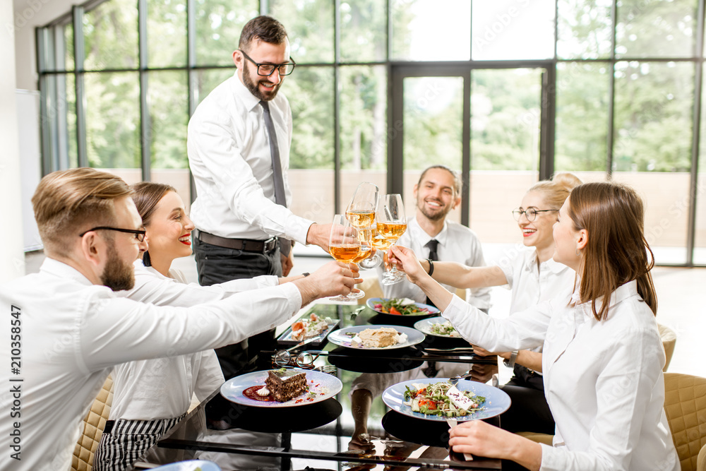 一群穿着白衬衫的商务人士在商务午餐时碰着酒杯