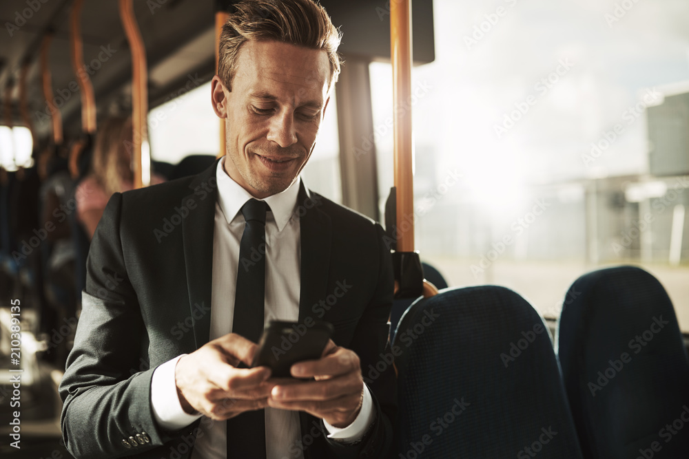 微笑的年轻商人在公交车上发短信