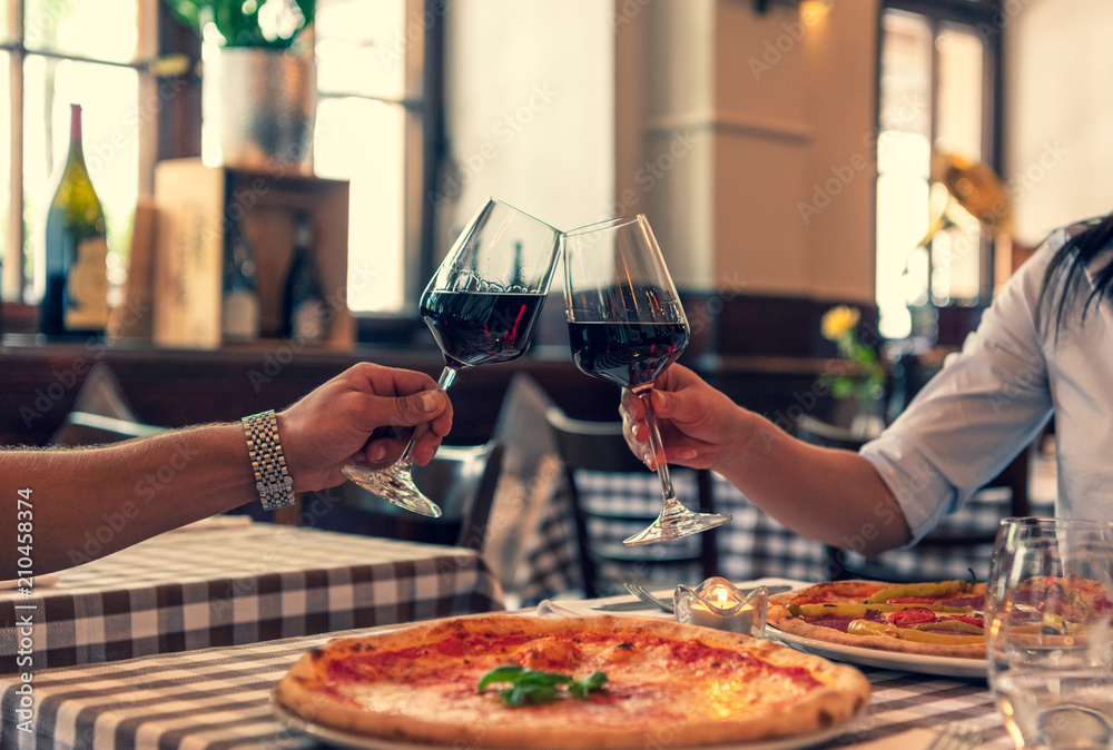 Verliebtes Paar stoßen auf Ihre Lieben an, halten Hand in einem Restaurant und essen Pizza und trink
