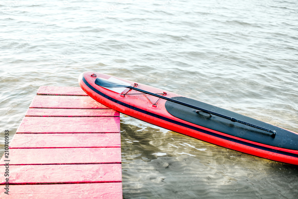 晨曦中湖边粉色码头上的红色桨板