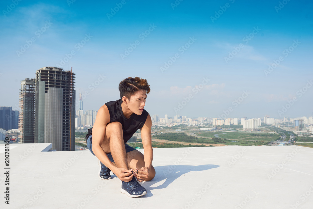 亚洲年轻男子户外跑步前系运动鞋带