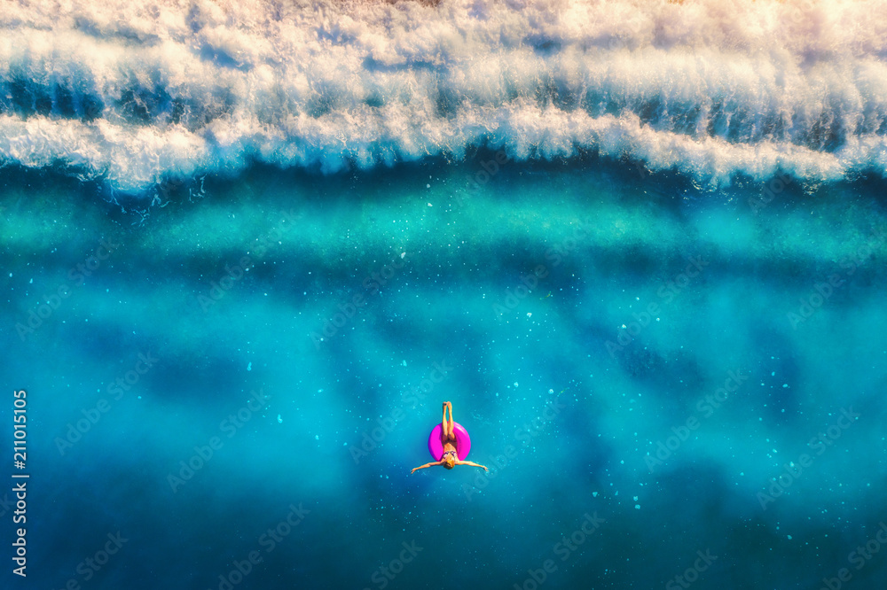 欧洲清晨，一名女子在粉色游泳圈上游泳的鸟瞰图。夏日之地