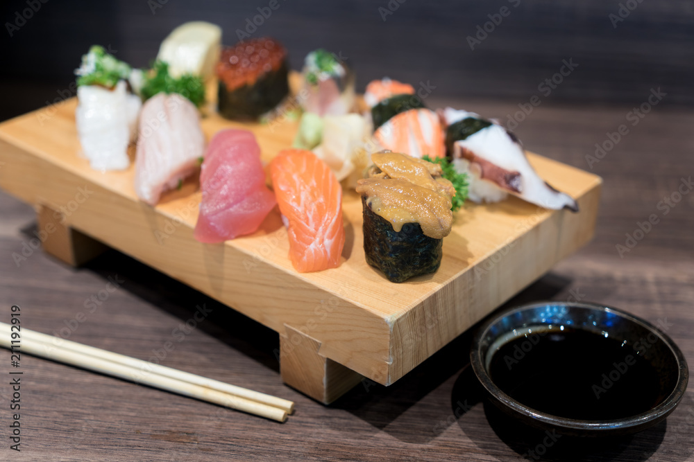 近距离观察寿司和生鱼片混合在黑色木桌上的木板上。日本食物。