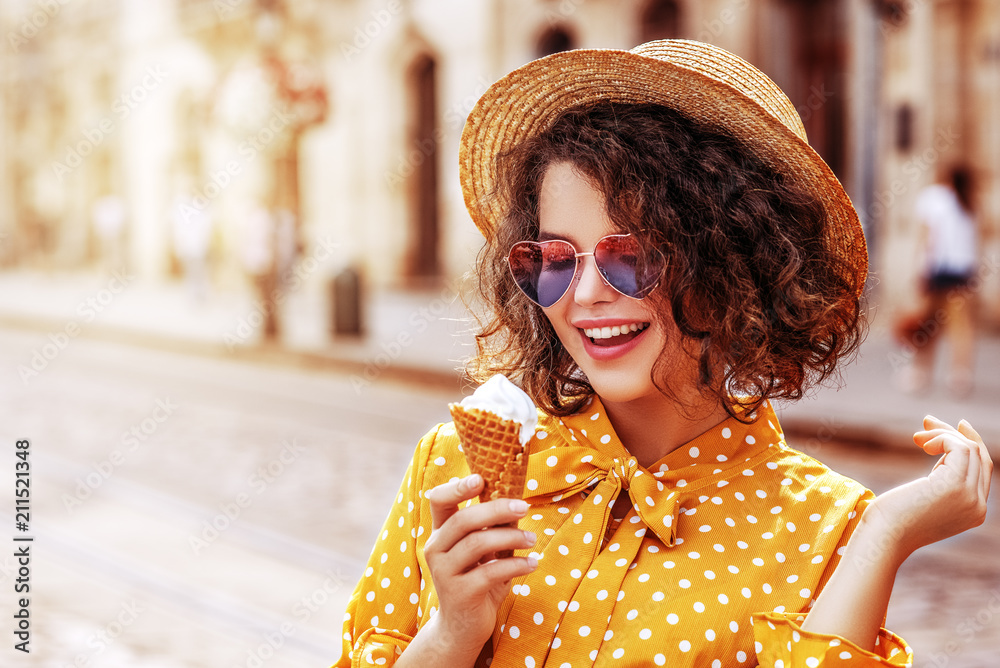 年轻漂亮的快乐女人拿着冰淇淋的户外特写。戴着草帽的模特，