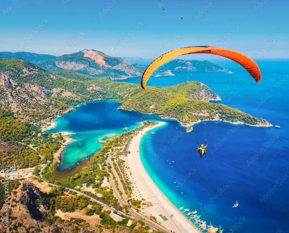 空中滑翔伞。滑翔伞双人组在碧水青山的海面上飞行