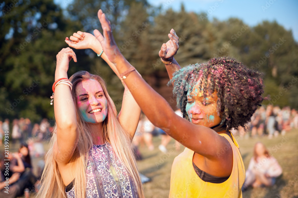 两个多民族女孩穿着五颜六色的粉末跳舞，庆祝暑假