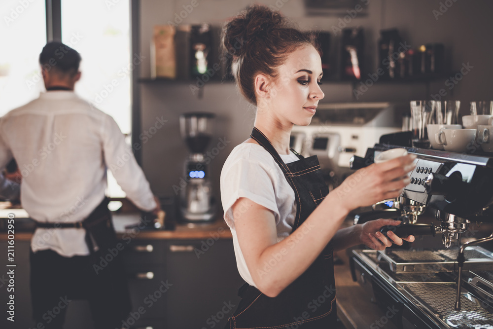 年轻女咖啡师在咖啡馆用机器准备咖啡