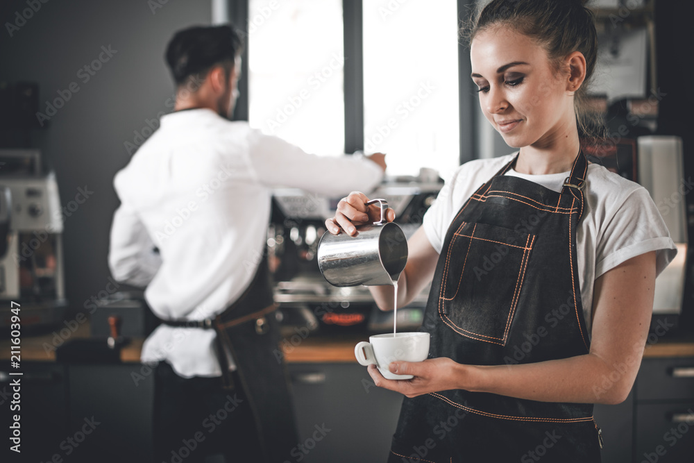 专业咖啡师女士在咖啡馆倒牛奶制作咖啡拿铁艺术
