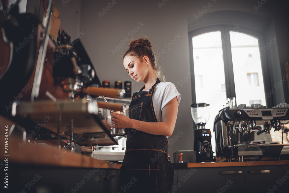 穿着围裙的职业咖啡师女士在咖啡馆用机器煮咖啡的肖像
