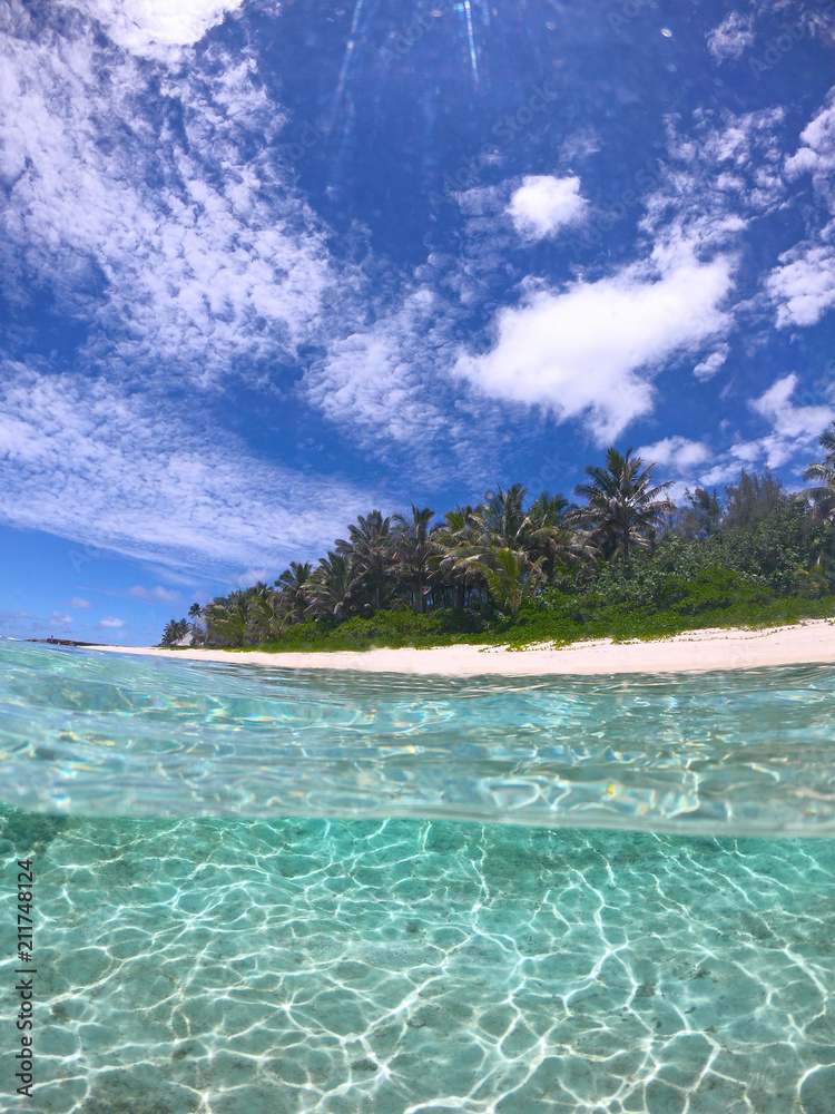 半水下：炎热的热带阳光照射在风景如画的空旷沙滩上。
