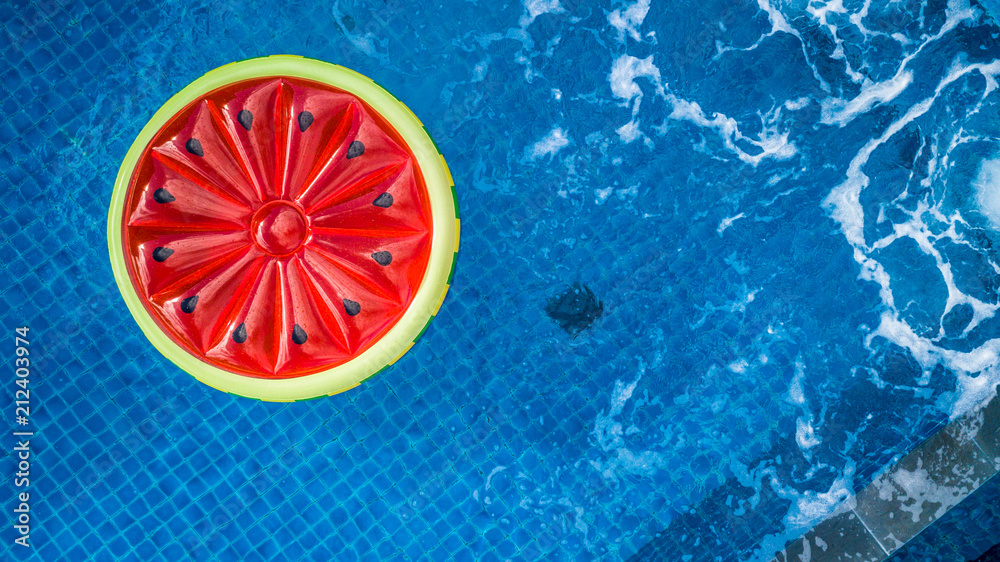 从上方俯瞰游泳池水中的彩色充气环西瓜玩具，夏季真空吸尘器