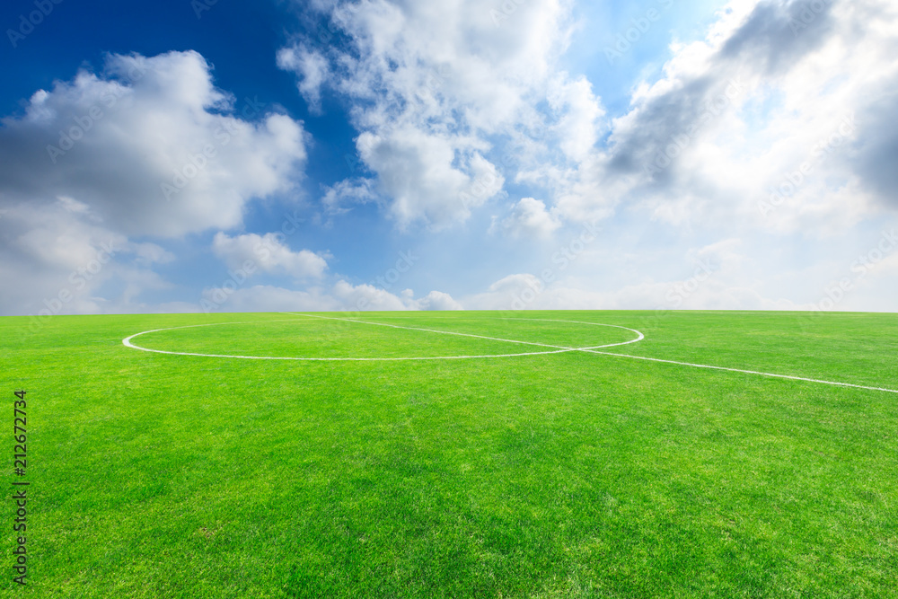 Green football field under blue sky background