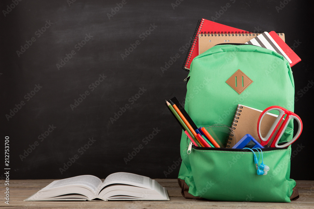 教育理念-带书本和其他用品的学校背包，黑板背景