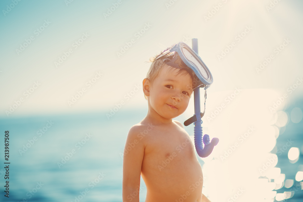 三岁男孩带着游泳圈在海滩玩耍