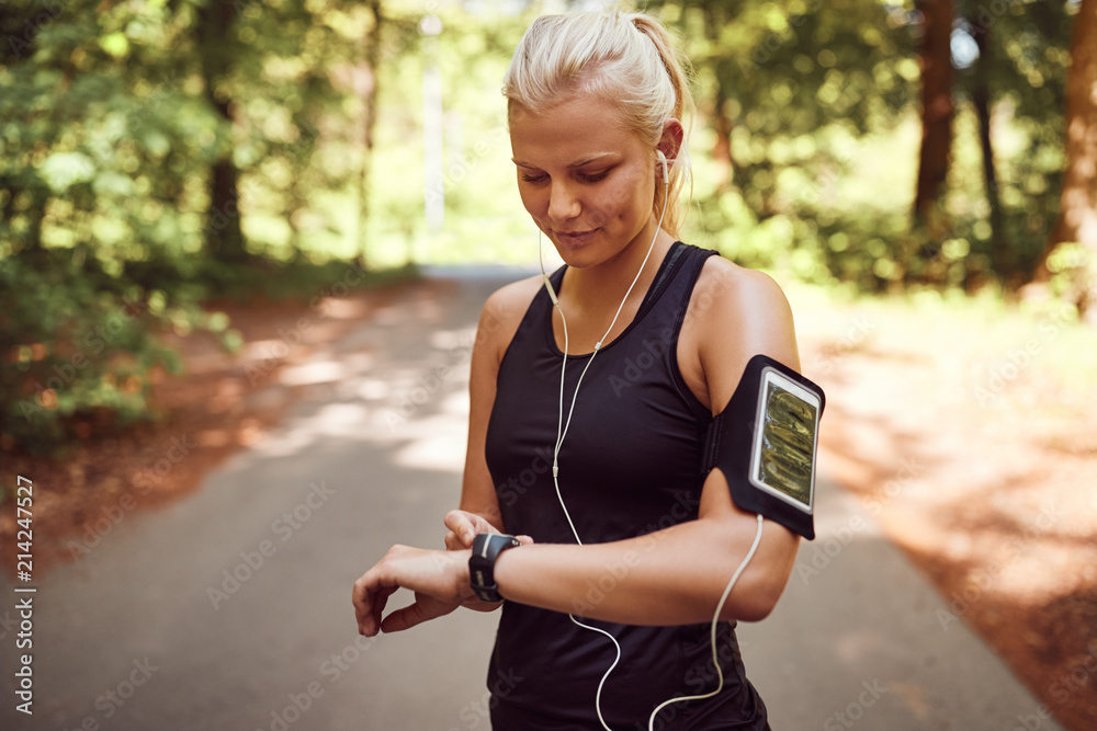 健康女性在森林跑步前设置运动手表