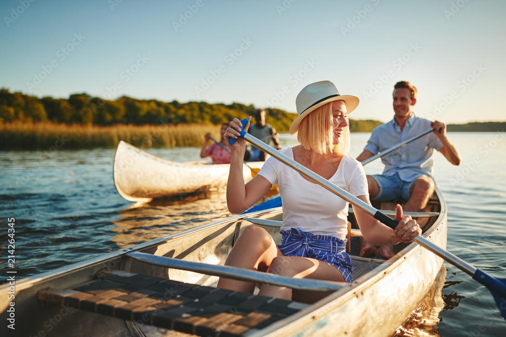 与朋友在湖上划独木舟的欢笑的年轻女子