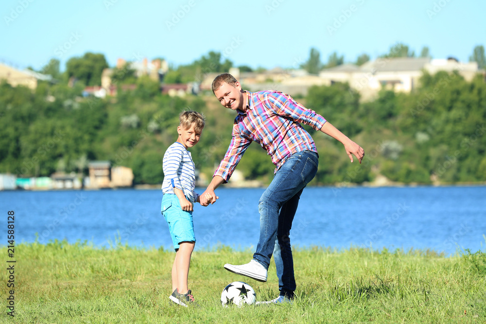 快乐的父子在河边踢足球