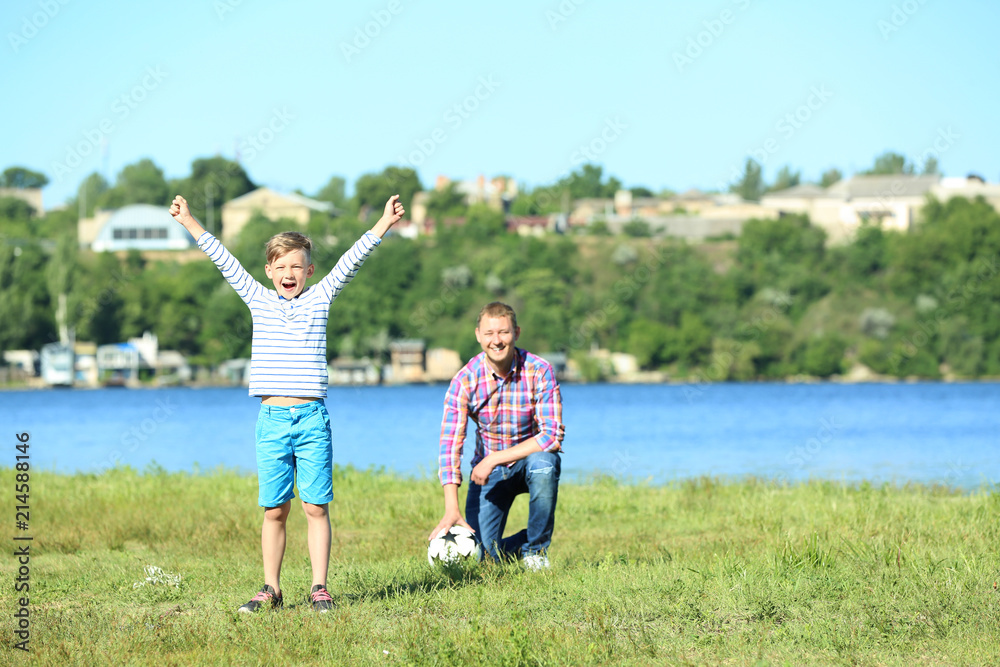快乐的父子在河边踢足球