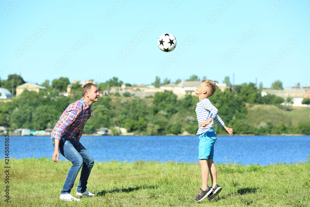 快乐的父子在河边踢球