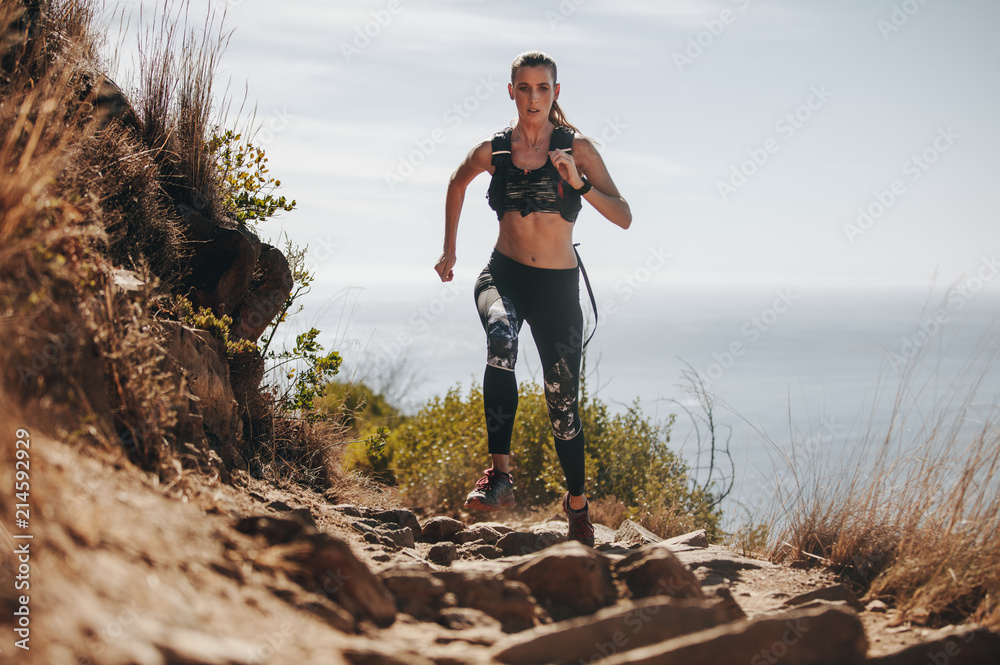 一名女子在山上的岩石小径上奔跑