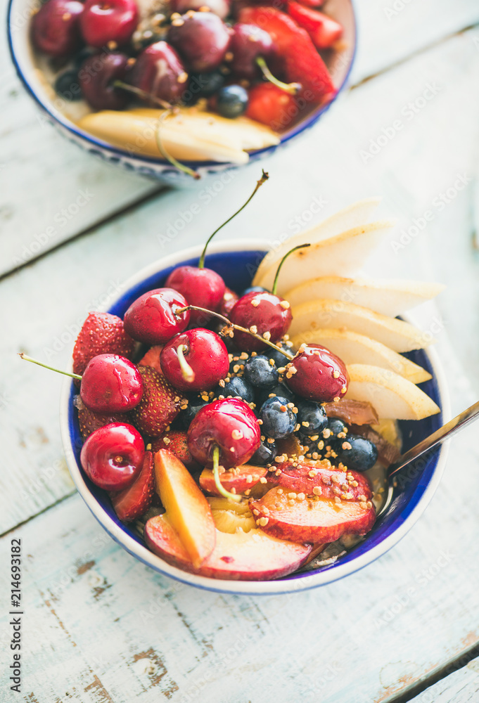 健康早餐冰沙碗，蓝色餐桌上有新鲜水果和浆果、蜂花粉和蜂蜜