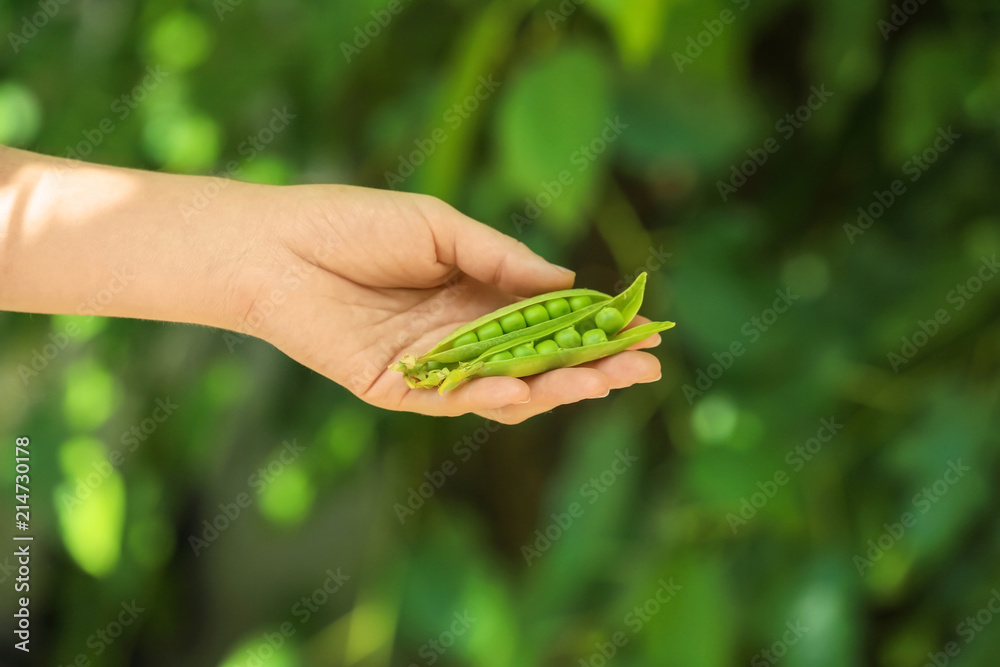 年轻女子在户外拿着新鲜的绿豌豆