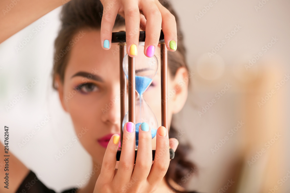 年轻女人，修着五颜六色的指甲，拿着沙漏，特写