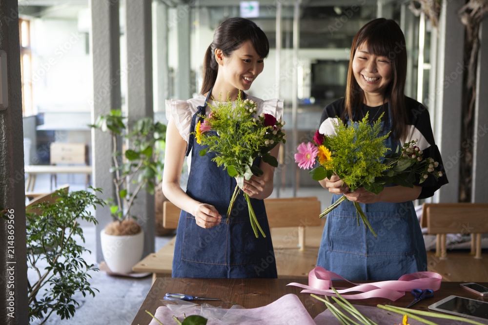 フラワーアレンジメント教室で花を手に取り微笑む女性二人
