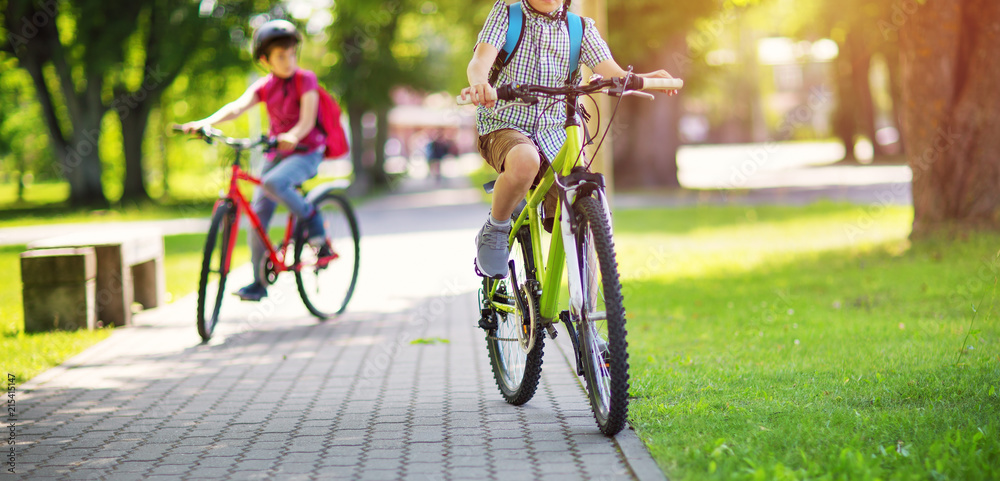 背着帆布背包的孩子在学校附近的公园里骑自行车。背着背包的学生在户外