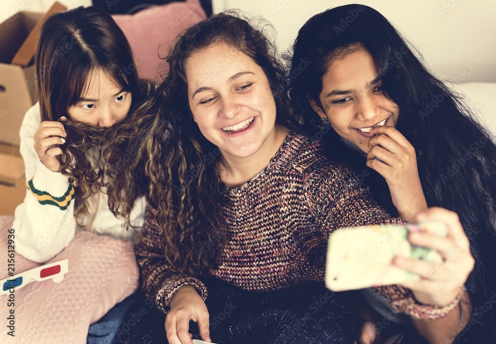 青少年女孩在卧室闲逛时使用智能手机自拍和友谊概念