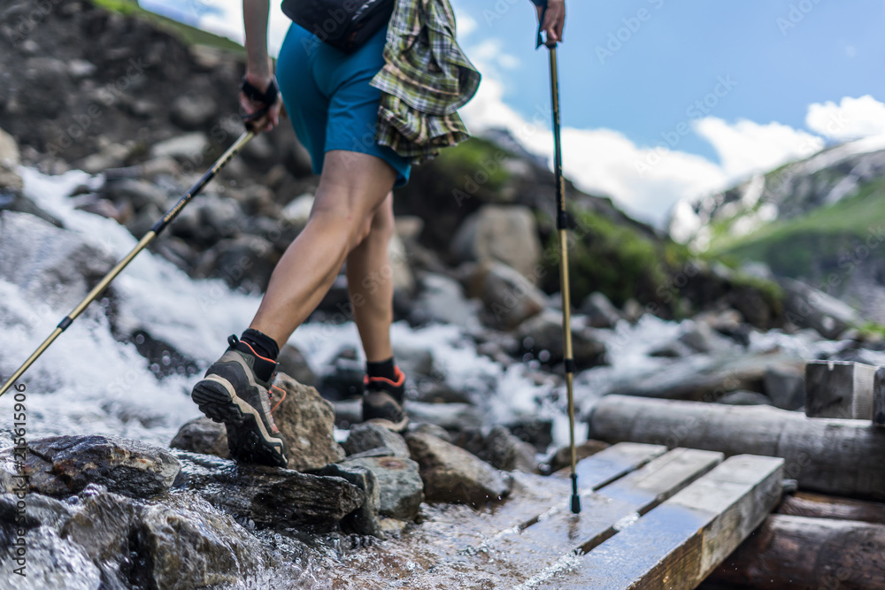 一名女子在阿尔卑斯山徒步旅行，穿着户外靴子和短裤，穿过木长椅和岩石