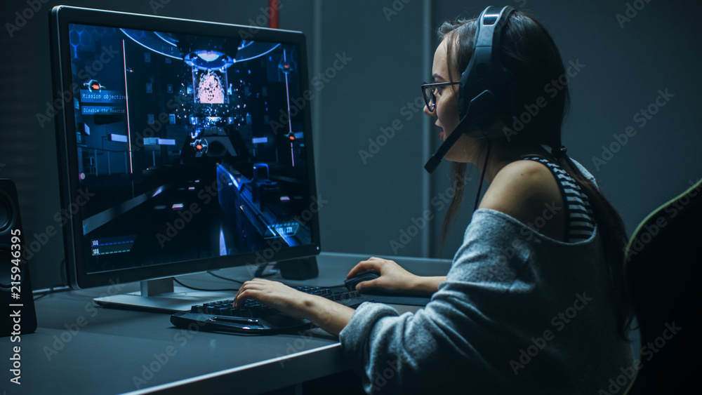 美丽的职业游戏女孩在个人电脑上玩第一人称射击游戏