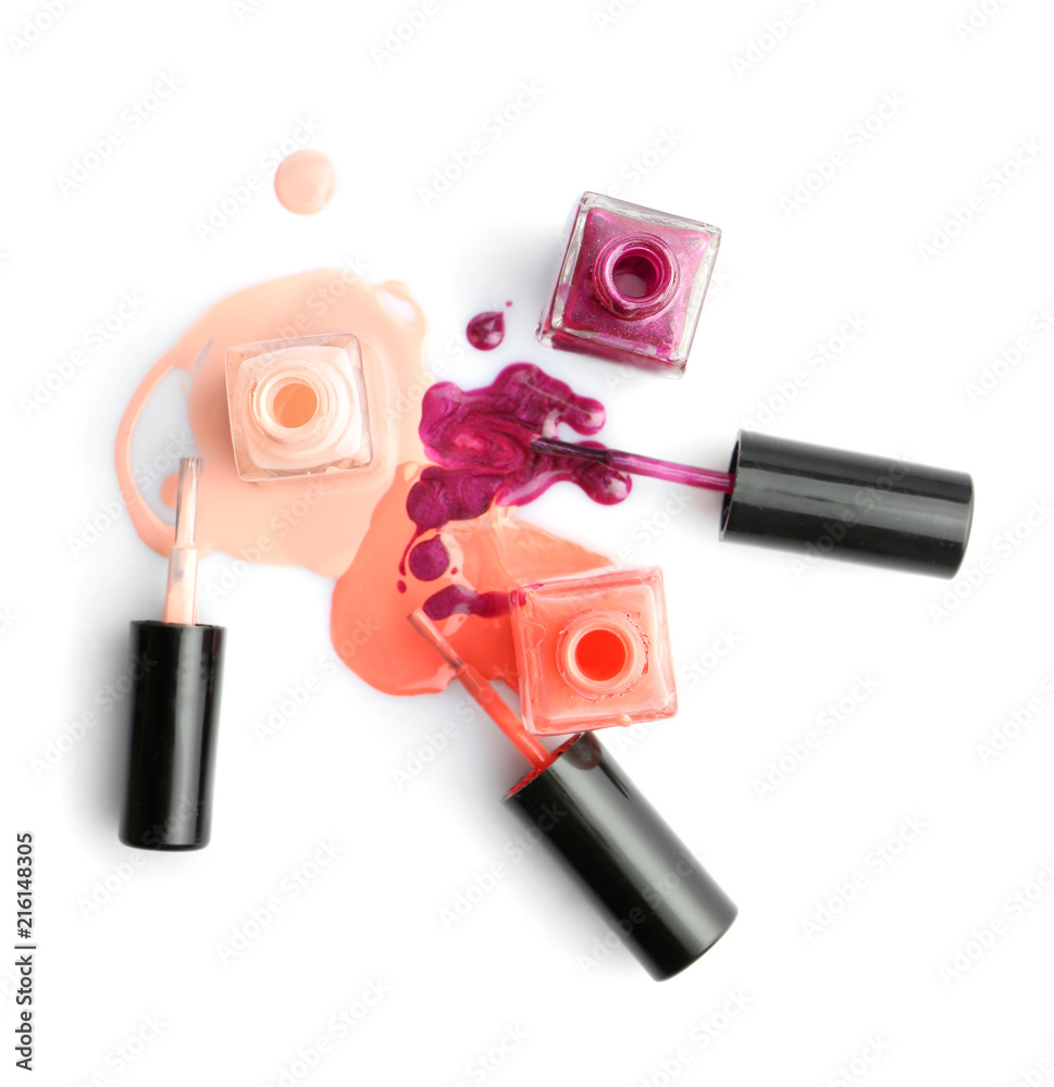Open bottles of nail polishes with brushes on white background