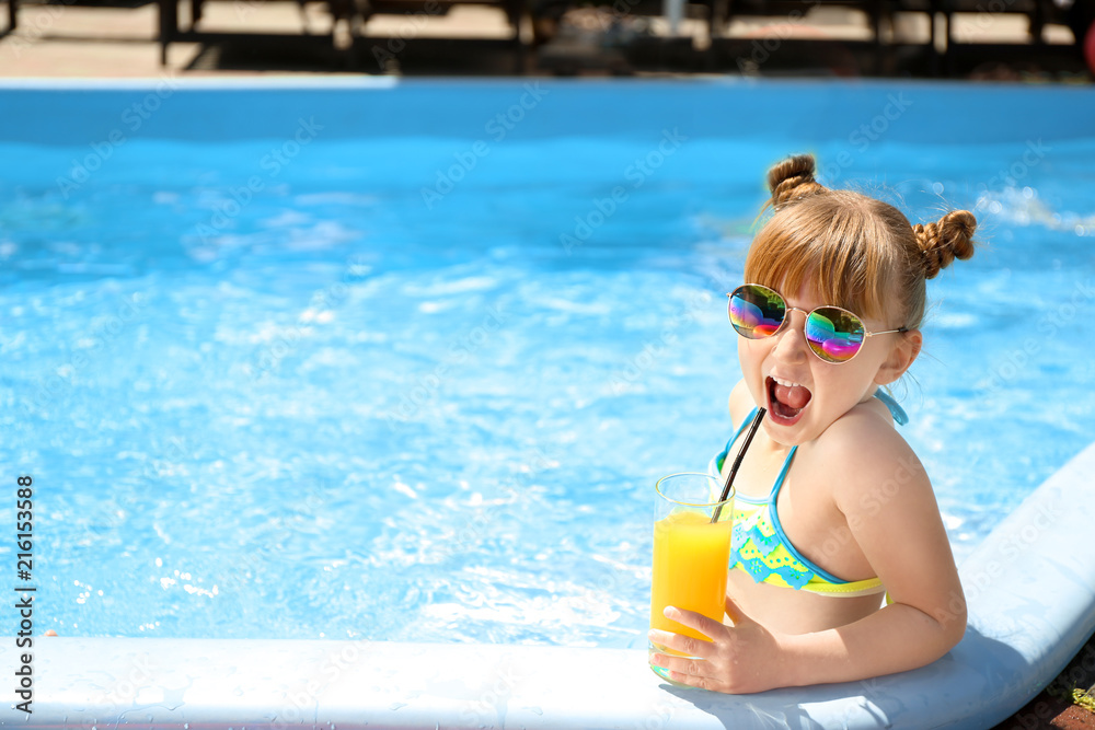 可爱的小女孩在游泳池喝果汁